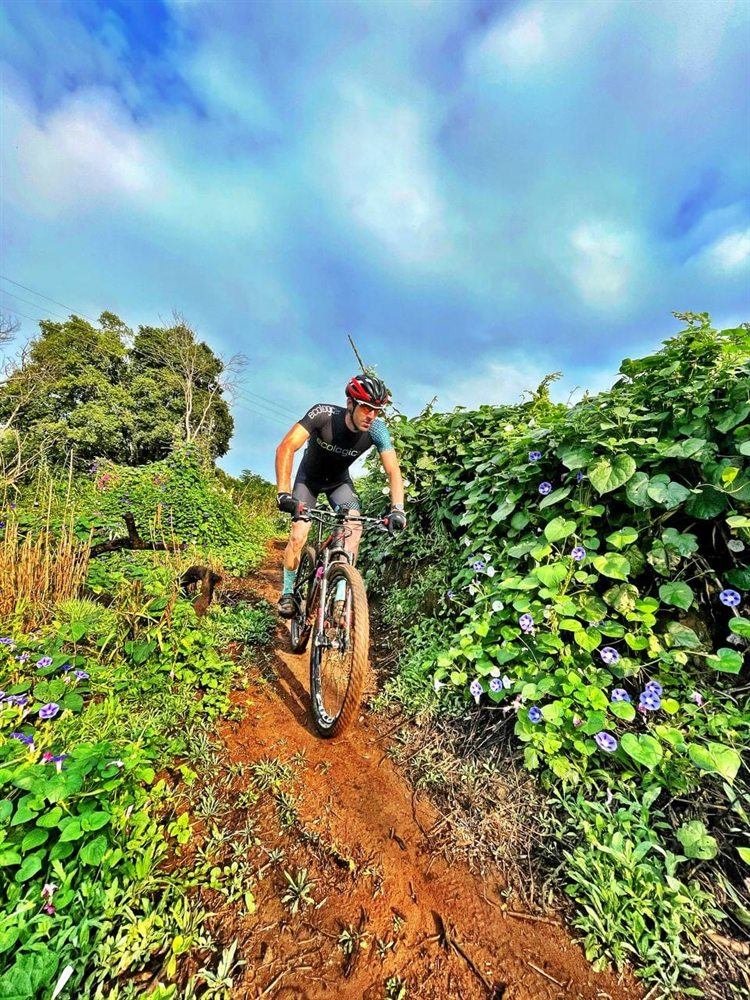Rider on lush green single-track along the River Trail at Van Gaalen